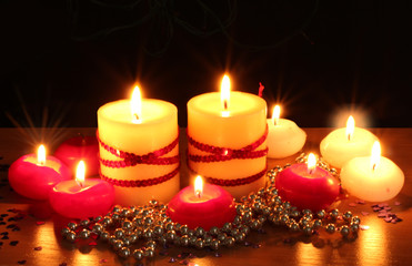 Beautiful candles and decor on wooden table on black background