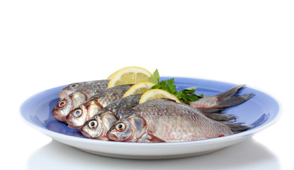 Fresh fishes with lemon and parsley on plate isolated on white