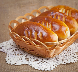 Ruddy pies in a wicker tray on the background of the canvas