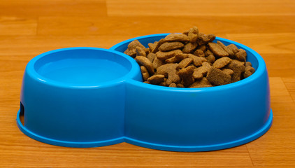 dry dog food and water in blue bowl on the floor