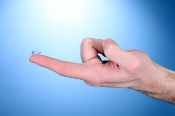 contact lens on finger on blue background