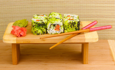 Tasty rolls served on wooden plate on wooden background