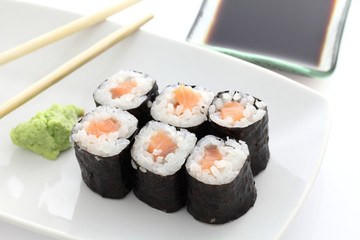 Salmon Maki sushi with chopsticks and soy sauce in white backgro