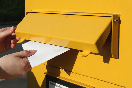Einwurf eines Briefes in einen Briefkasten