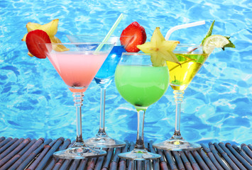 Glasses of cocktails on table on blue sea background