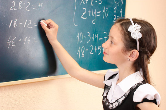 beautiful little girl writing on classroom board