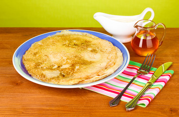 Stack of tasty pancakes on wooden table on green background