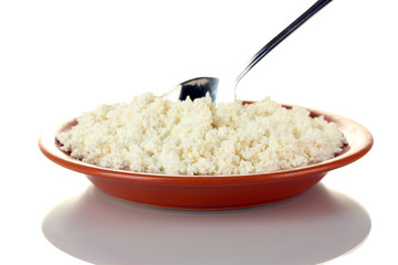 Spoon scoops of cottage cheese in a plate on white background
