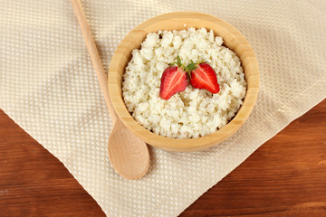 cottage cheese with strawberry in wooden bowl with wooden spoon