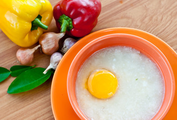 Rice porridge with egg in orange bowl.