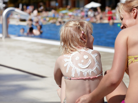Mother and child with sunblocker on the back in open-air bath