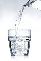 Filling a glass with water on a light blue background