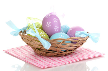 Colorful easter eggs in basket on napkin isolated on white