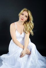 Fototapeta premium beautiful blonde in white gown on gray background