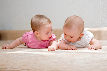 Two sisters, twin baby girls talking and lying together