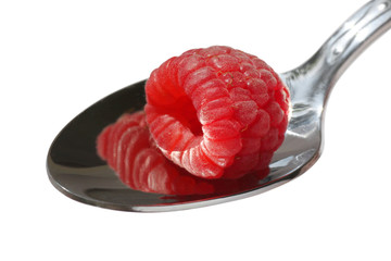 close up of raspberry on a spoon over white