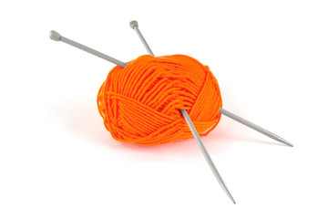 Ball of orange wool with knitting needles on white