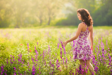 Naklejka na ściany i meble Piękna młoda kobieta w fioletowe kwiaty na zewnątrz