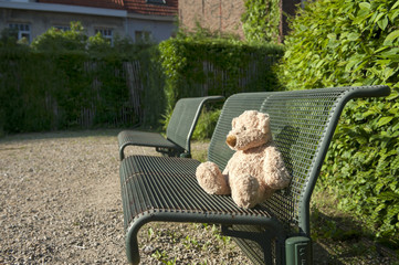 lost teddy bear seated on a iron bench
