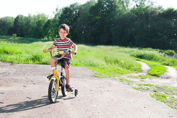 Obraz premium Little boy riding bike on country road outdoors