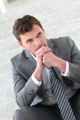 Portrait of depressed businessman sitting in stairs