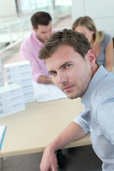 Portrait of man sitting in office with colleagues