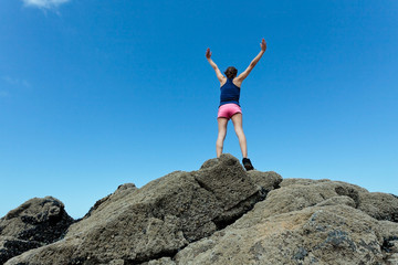 Fitness girl on top of rocks with arms wide open