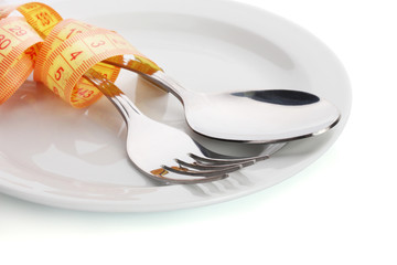 Fork, spoon and measuring tape on plate isolated on white