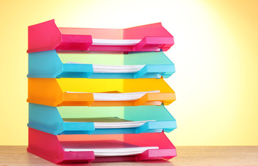 bright paper trays on wooden table on yellow background