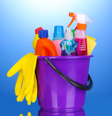 Bucket with cleaning items on blue background