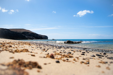Fototapeta na wymiar Beach, volcanic dark stones and blue sky
