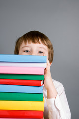 Boy looks out from a stack of books