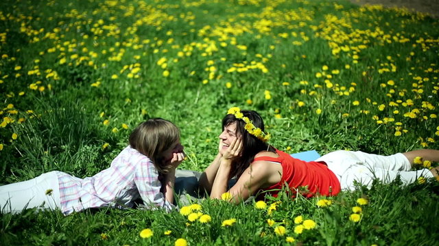 Mother with daughter lying on meadow and chatting together