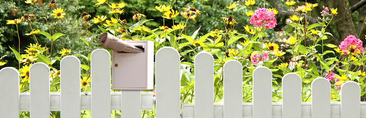 Gartenzaun mit Briefkasten und Zeitung
