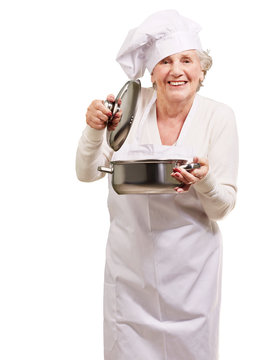 portrait of cook senior woman opening sauce pan over white