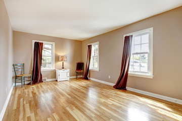 Empty large room with three windows and hardwood.