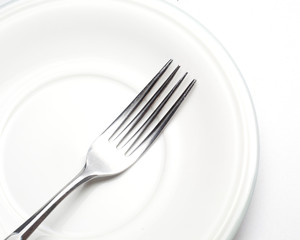 White plate, fork on light background.