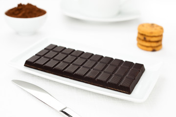 Chocolate dark tablet, cocoa, cookies on white tablecloth