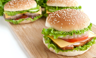 three burger with meat and vegetables on wood plate