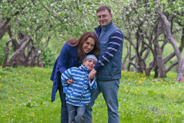 Fototapeta premium Happy young family of three have fun in apple garden