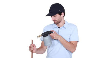 Plumber heating pipe with blow-torch