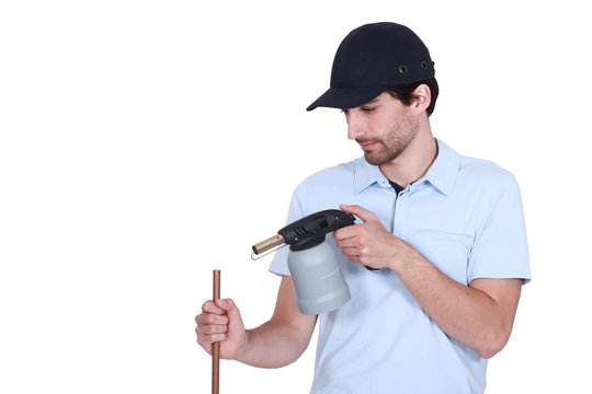 Plumber heating pipe with blow-torch