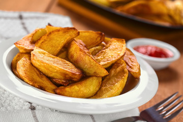 Fresh homemade crispy fried potato wedges on plate