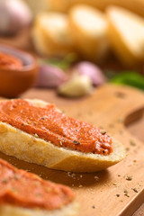Tomato-butter spread on baguette slices with ground pepper