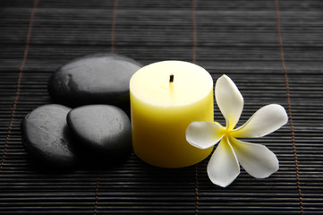 Fototapeta na wymiar kamienie spa, świece i kwiaty frangipani tropikalnych na mata bambusowa