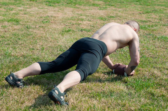 American football player doing push ups exercise on a playfield