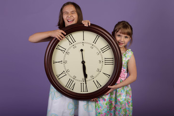 Two laughing girls holding a large wall clock