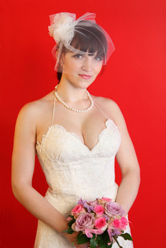 bride wearing white dress holds bouquet of roses on red