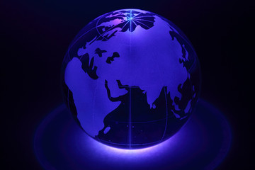 Small glass globe is illuminated by blue light from below