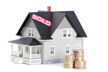 Stacks of coins in front of household architectural model
